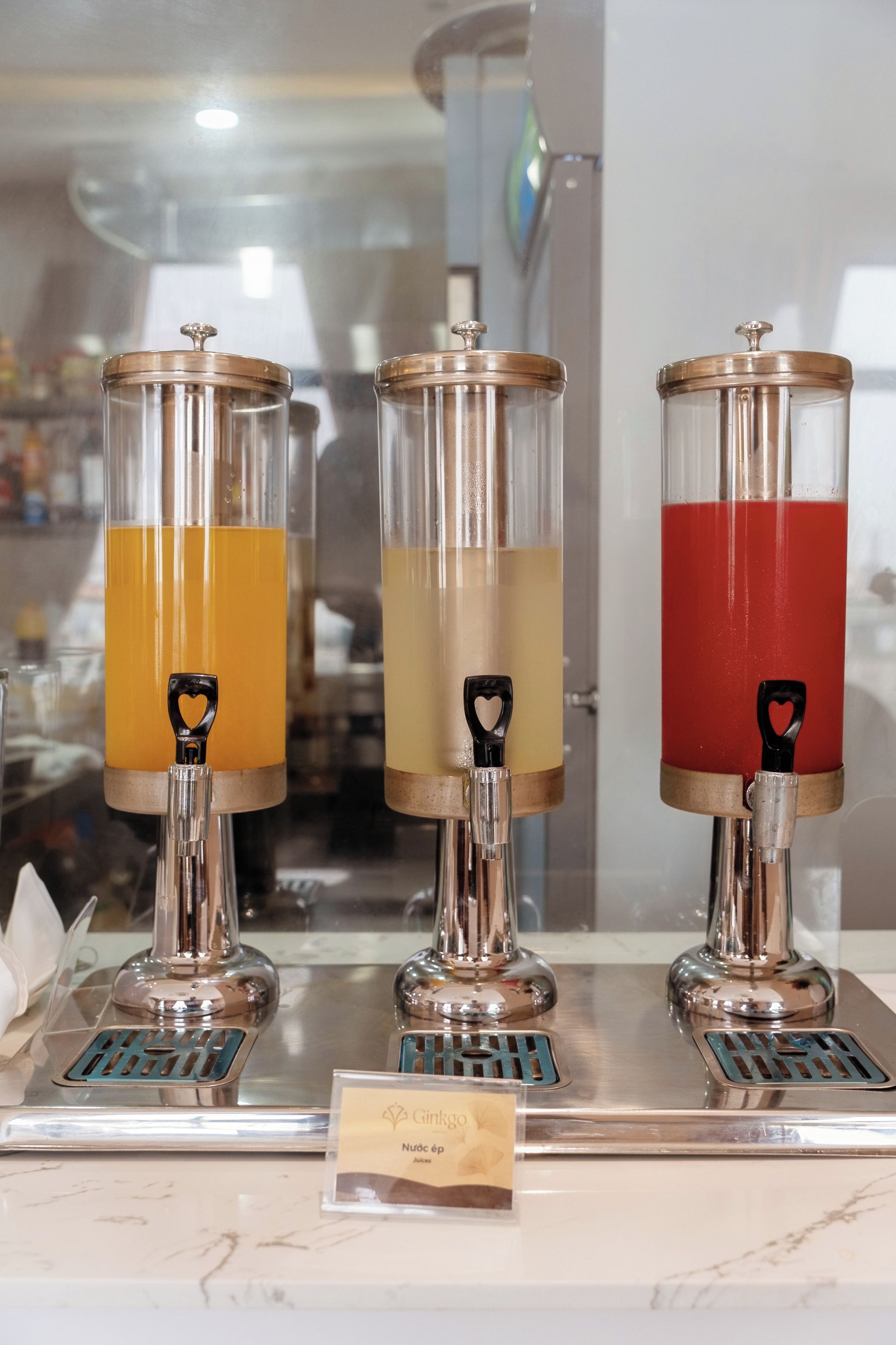 A juice dispenser with three different colored liquids, each with a heart-shaped handle.