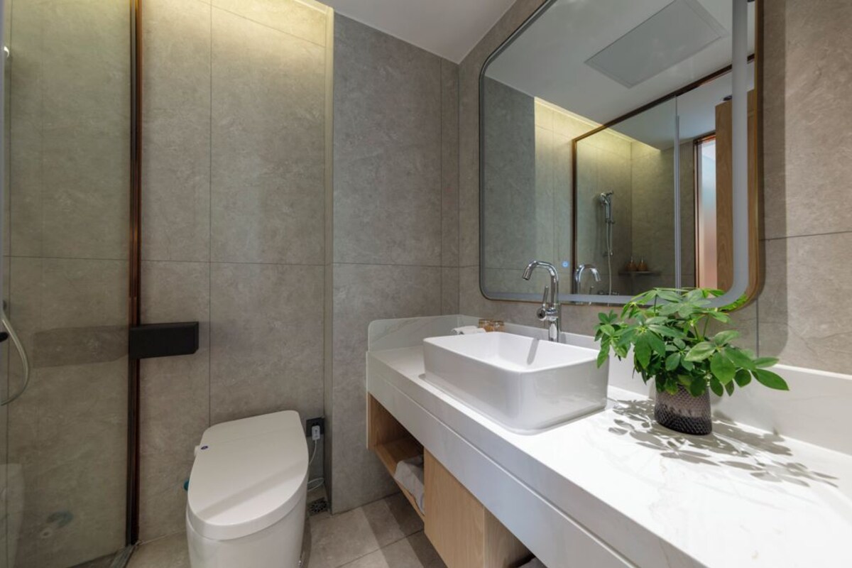 A modern bathroom with a white toilet, a large sink, and a mirror above it.