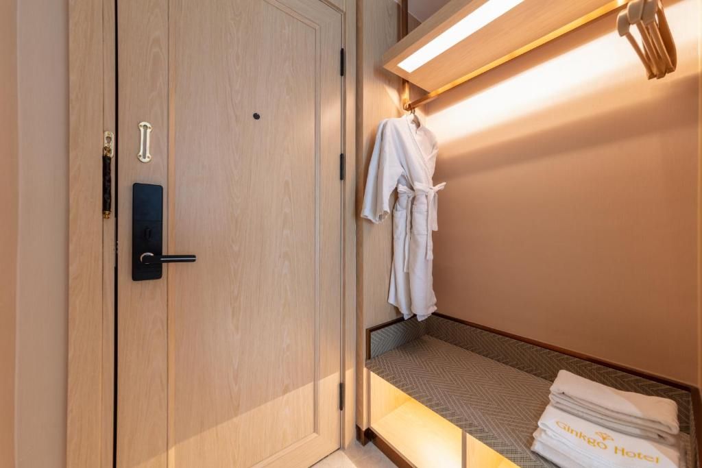 A hotel room with a wooden wardrobe, a bed with a patterned bedspread, and a hanging robe.