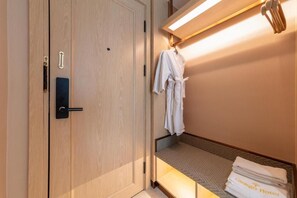 A hotel room with a wooden wardrobe, a bed with a patterned bedspread, and a hanging robe. - Ginkgo Hotel Hanoi (Hanoi)