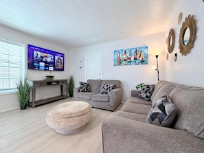 Ein Wohnzimmer mit Flachbildfernseher, einem Gemälde und einer Couch.