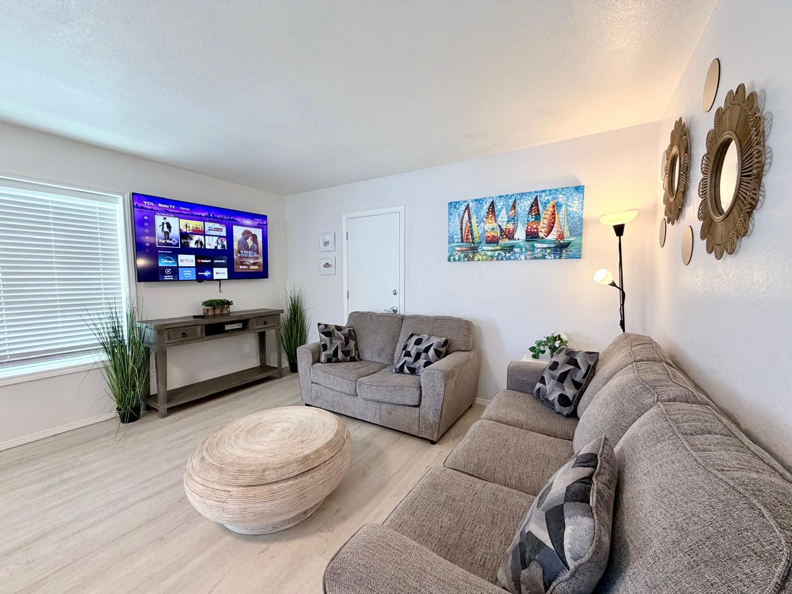 A living room with a flat-screen TV, a sofa, a coffee table, and decorative wall art.