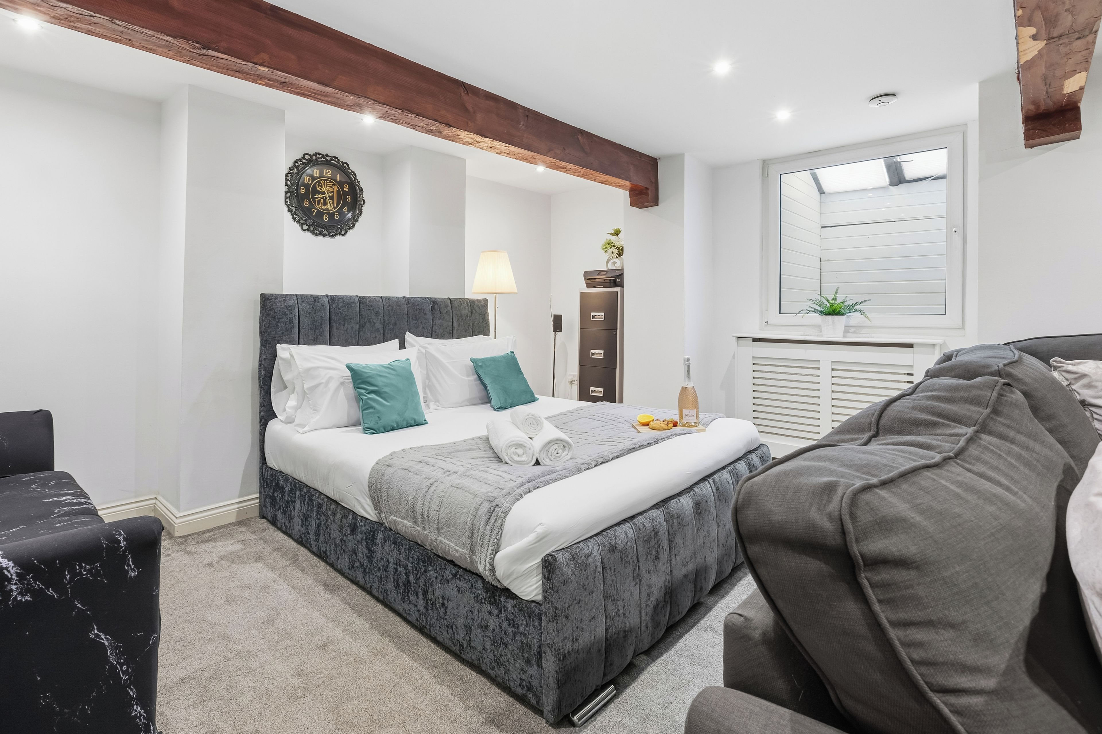 A modern bedroom with a bed, bedside table, lamp, and a decorative wall clock.