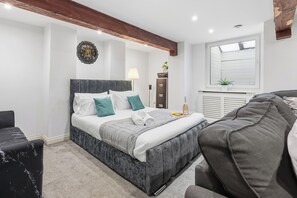 A modern bedroom with a bed, bedside table, lamp, and a decorative wall clock. - The Cozy Snug Basement, Sleeps 2 in Bury (Bury)