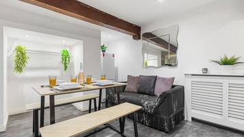 Un'area living moderna con tavolo da pranzo, panca, divano e parete specchiata.