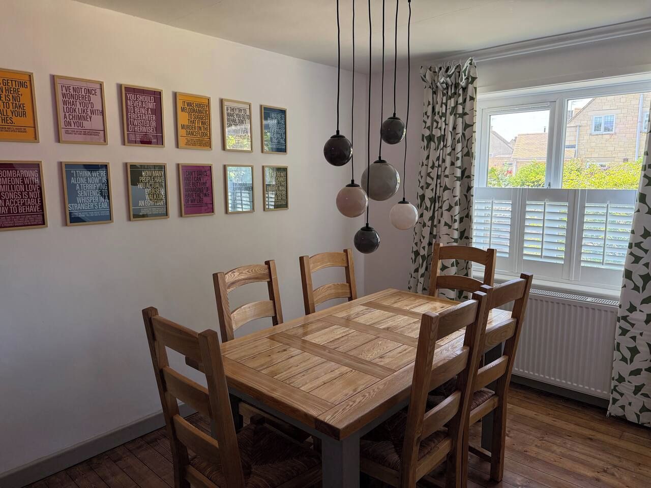 Ein Essbereich mit Holztisch und Stühlen, umgeben von Wänden mit gerahmten Sprüchen.