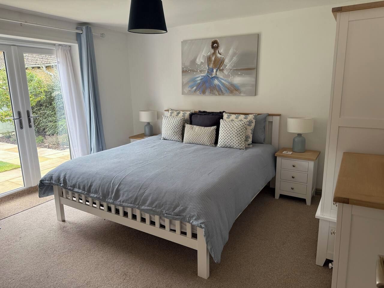 Ein Schlafzimmer mit einem Bett, Nachttischen, einem Gemälde und einem Kleiderschrank.
