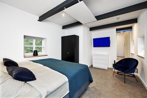 A modern bedroom with a bed, a wardrobe, a TV, and a chair. - Stellwerk Ringelstein: Forest-Edge Retreat with Sauna, Fireplace, Terrace & Wi-Fi (Büren)