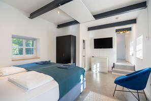 Un dormitorio moderno con cama, escritorio, silla y televisión.