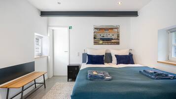 Ein Hotelzimmer mit einem Bett, einer Sitzbank, einer kleinen Kommode und einem Bild an der Wand.