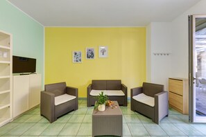 A room with two wicker sofas, a small table with a plant, and a television on a cabinet.
