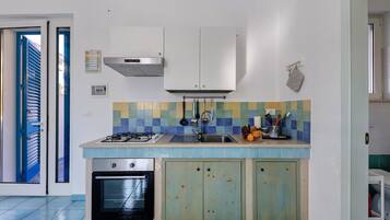 Una cucina compatta con piano cottura a gas, forno e rivestimento in piastrelle.