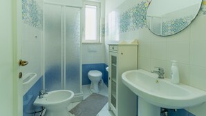 Un baño con ducha, inodoro, bidé, lavamanos y espejo.