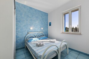 Een slaapkamer met een bed, een raam en een blauwe muur.