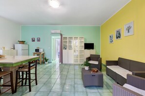 Un espacio habitable compacto con kitchenette, comedor y zona de estar.