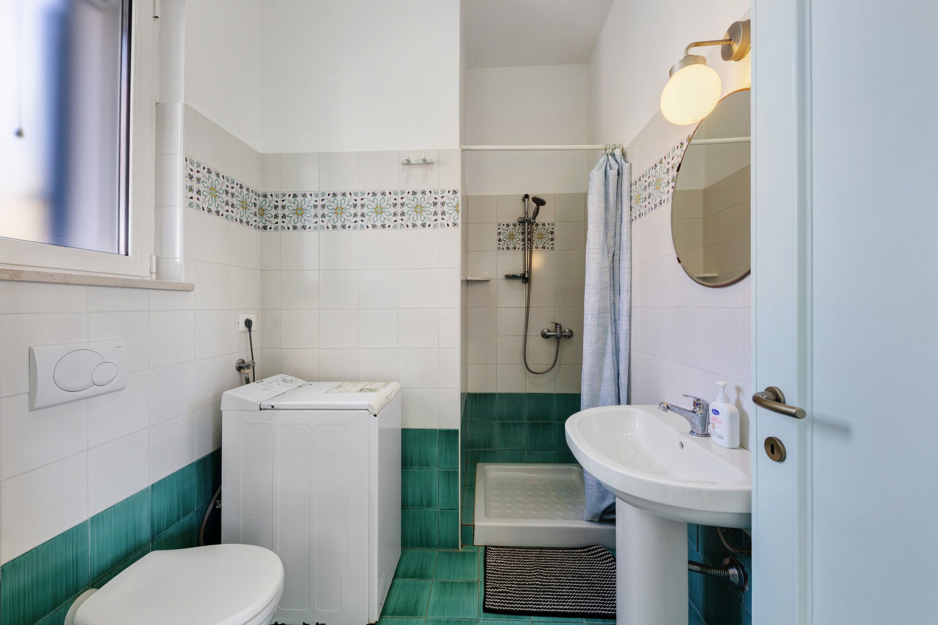 A bathroom with a toilet, a sink, a shower, and a mirror.