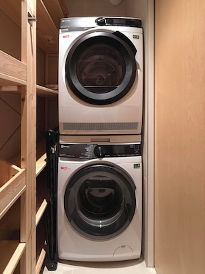 A stacked washer and dryer unit in a wooden cabinet. - Serenity77 · 100m² designed by an architect, Geneva (Vandœuvres)