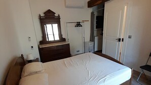 A bedroom with a bed, a dresser, a mirror, a wardrobe, and a door. - Vrbo Property (Saint-Ferriol)