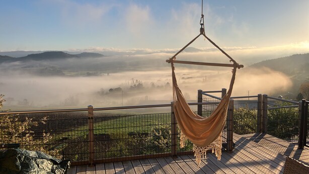 A hammock on a wooden deck overlooking a misty valley with distant mountains. - Vrbo Property (Saint-Ferriol)