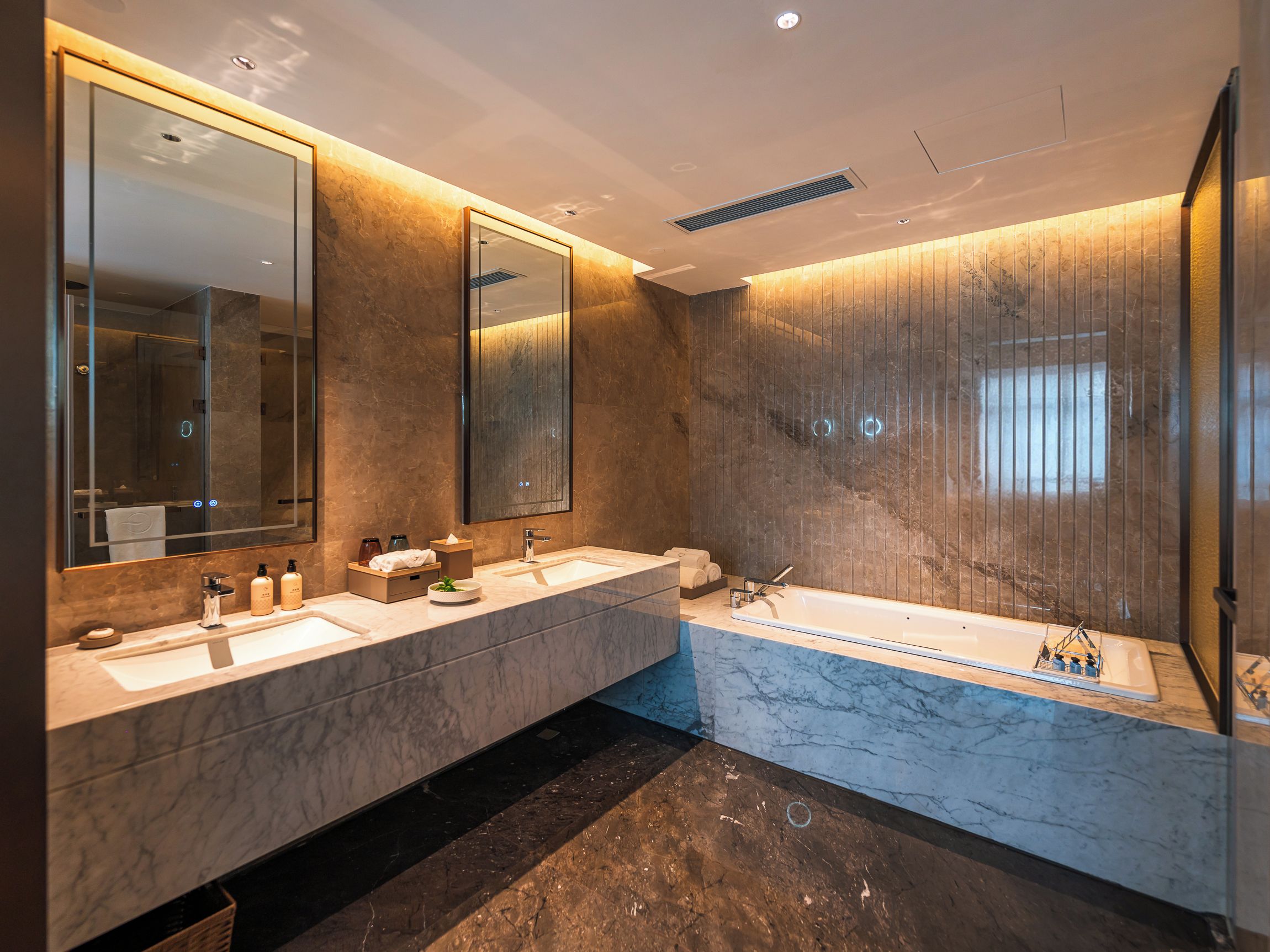 Un baño moderno con dos lavamanos, un espejo grande y una bañera.