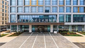 A modern building with a glass facade, a large entrance, and a parking lot.