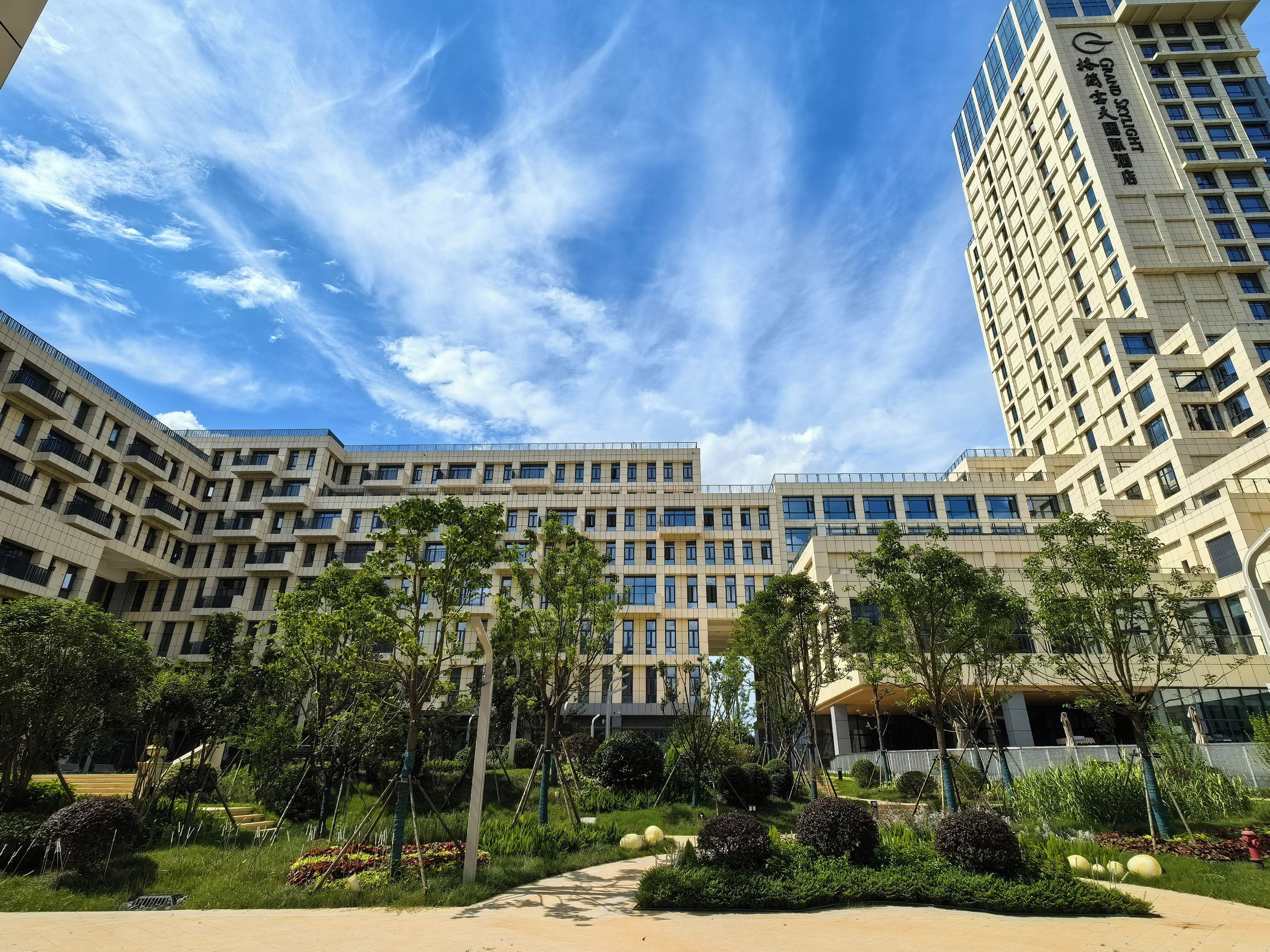 A multi-story building with a modern architectural design, featuring a central courtyard with greenery and pathways.
