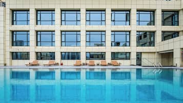 A modern building with a pool, multiple windows, and outdoor seating.