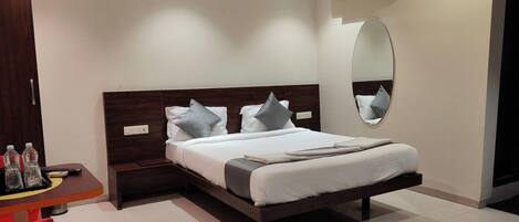 A hotel room with a bed, bedside table, and a mirror.
