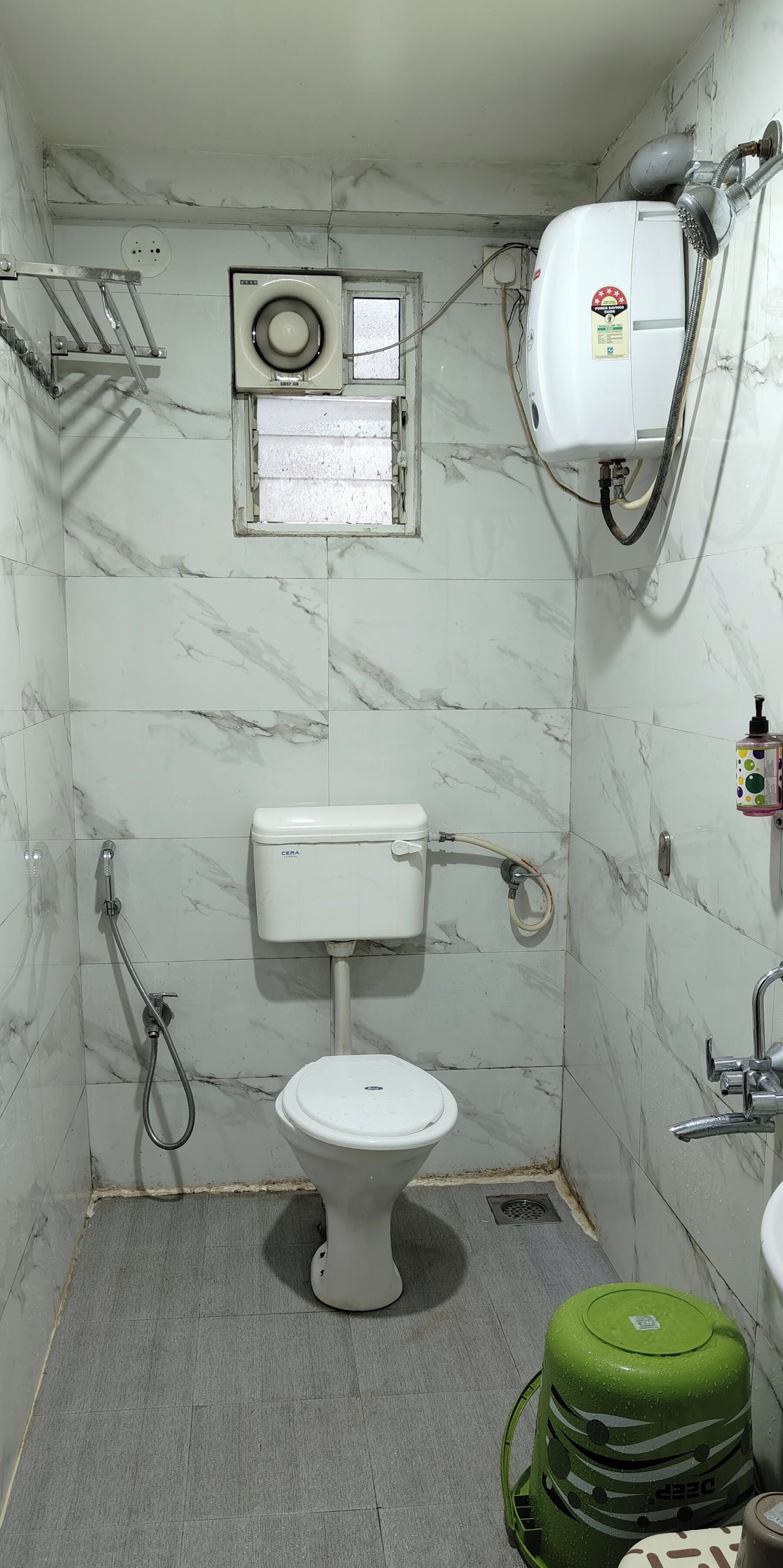 A small, compact bathroom with a toilet, a shower, and a water heater.