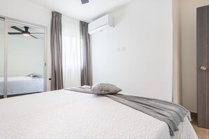 Ein Schlafzimmer mit einem Bett, einem Deckenventilator, einer Klimaanlage und einer Tür.