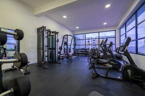 Ein Fitnessstudio mit verschiedenen Trainingsgeräten, großen Fenstern und Blick auf Gebäude.
