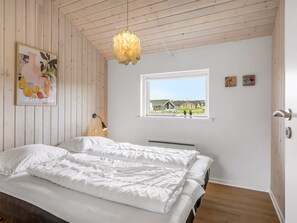 A bedroom with a bed, a window with a view, and a hanging light fixture. - "Clarice" - 250m to the fjord by Interhome (Vinderup)