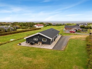 A modern house with a deck, surrounded by a well-maintained lawn and a view of the sea. - "Clarice" - 250m to the fjord by Interhome (Vinderup)