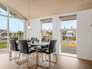 A modern dining area with a table and chairs, large windows, and a wooden ceiling. - "Clarice" - 250m to the fjord by Interhome (Vinderup)
