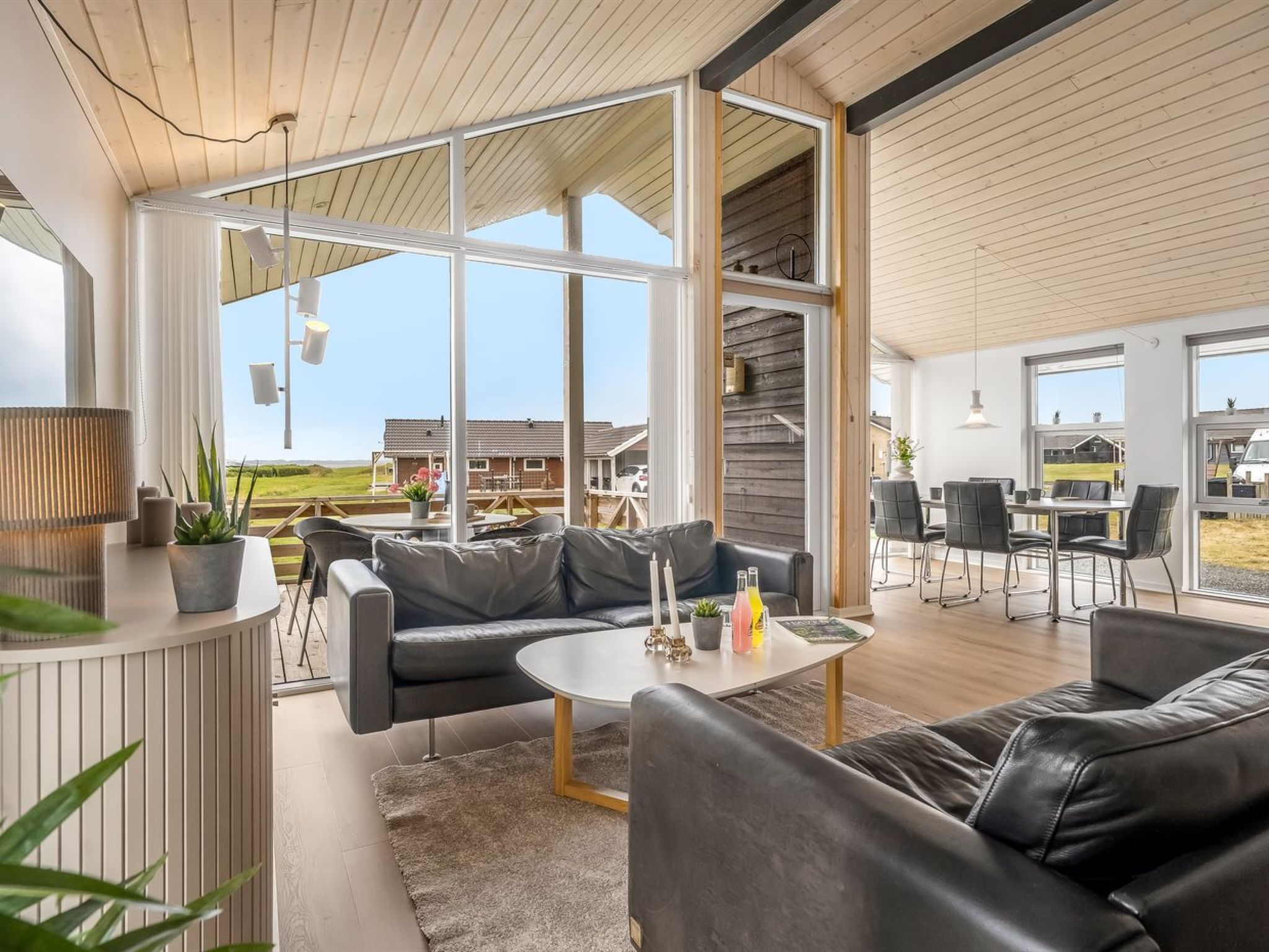 A modern living room with leather sofas, a coffee table, and a view of the outdoors.