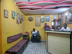 A reception area with a bench, a fan, and a wall with framed pictures. - Classic RIO Patna (Patna)