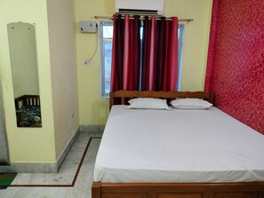 A bedroom with a bed, a window with curtains, an air conditioning unit, and a mirror. - Classic RIO Patna (Patna)