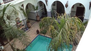 Piscina interna com várias arcos e plantas em vasos.