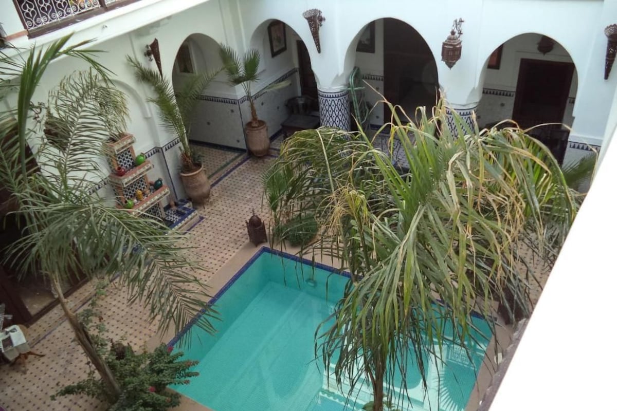 An indoor swimming pool with multiple arches and potted plants.