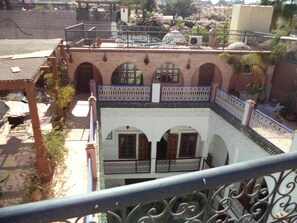 A courtyard with a white building featuring arched windows and a blue railing. - Dar moulay Ali (MARRAKECH)