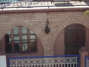 A building facade with arched windows and a door, a decorative metal gate, and a patterned wall. - Dar moulay Ali (MARRAKECH)