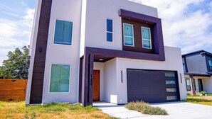 Een modern huis met twee verdiepingen, een garage, grote ramen en een houten omheining.