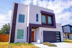 Una casa moderna de dos pisos con garaje, ventanas grandes y cerca de madera.