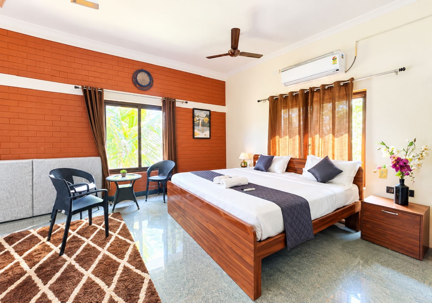 Habitación de hotel con cama, escritorio, silla, ventana con cortinas, ventilador de techo y aire acondicionado.