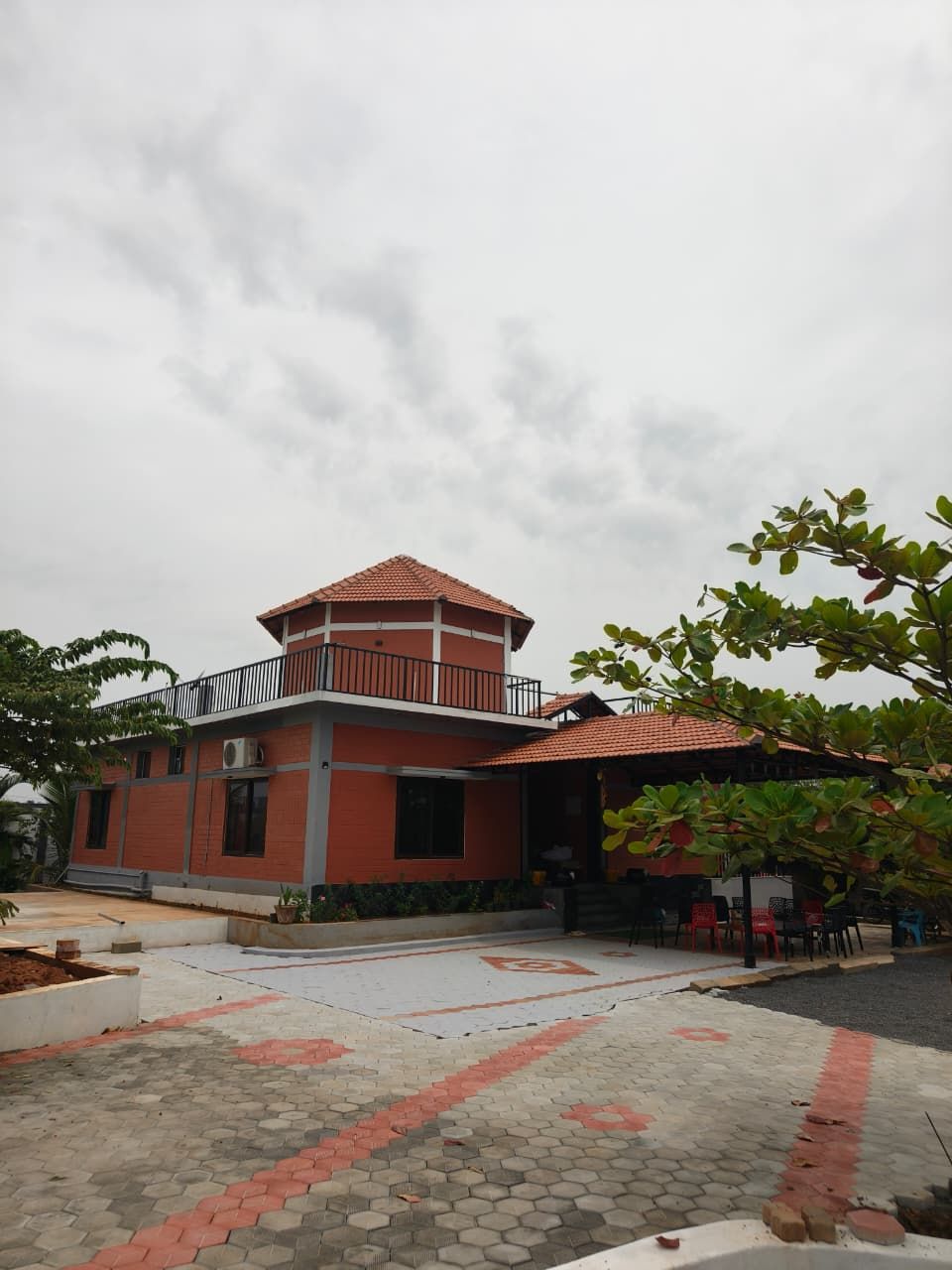 A building with a red-tiled roof, a balcony, and a paved courtyard.
