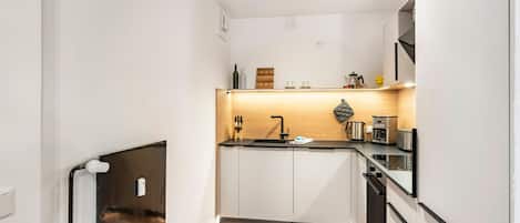 A compact kitchen with white cabinets, a wooden countertop, and modern appliances.