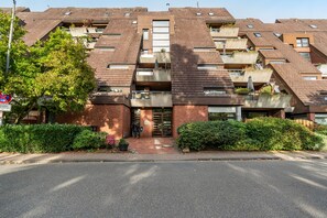 Ein mehrgeschossiges Wohngebäude mit Ziegelverkleidung, mehreren Balkonen und einem verschlossenen Eingang.