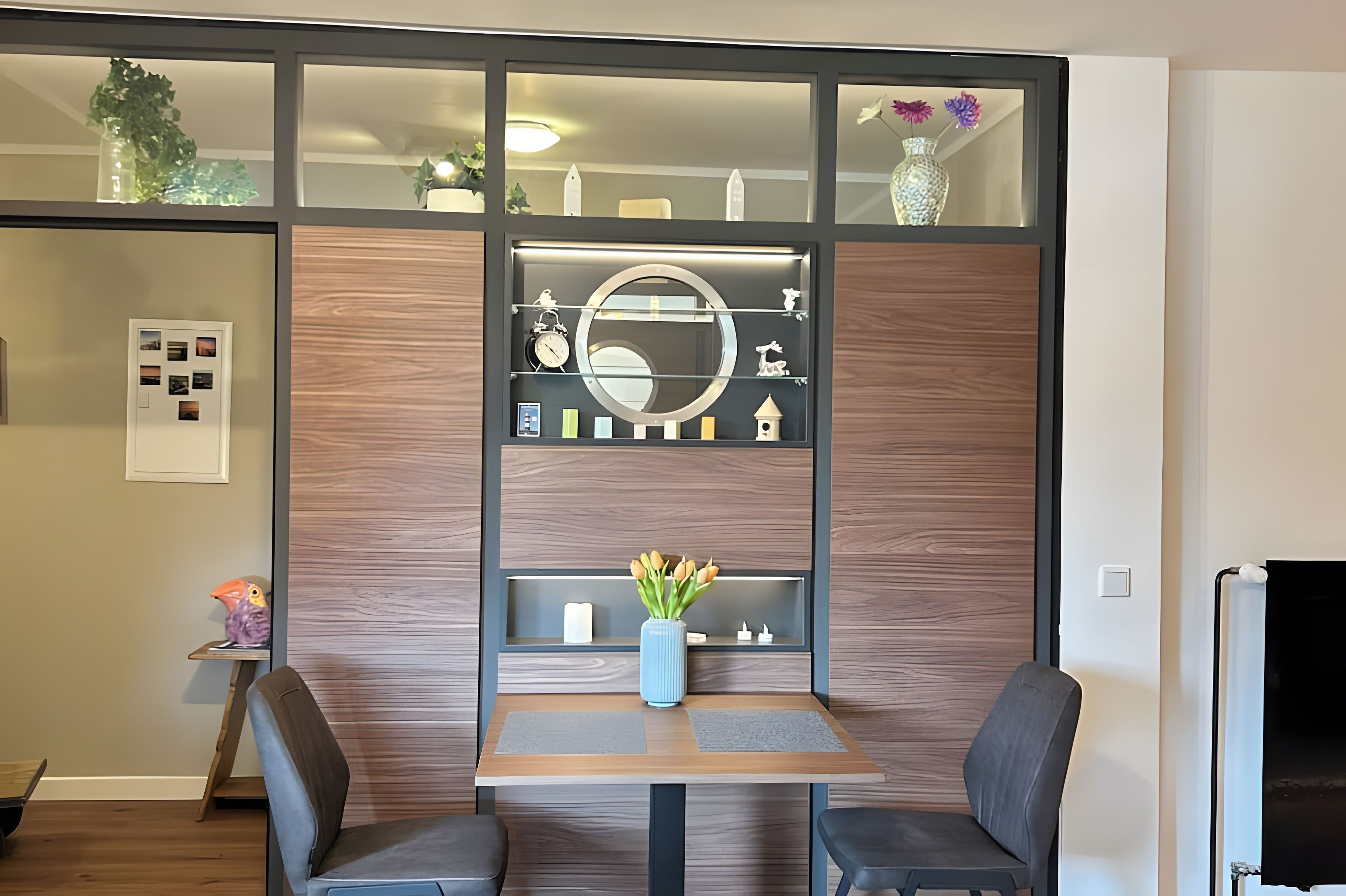 A modern room with a wooden panel wall, a round mirror, and a small table with chairs.