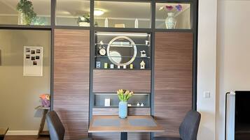 A modern room with a wooden panel wall, a round mirror, and a small table with chairs.