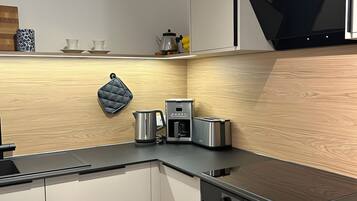 A modern kitchen with a built-in coffee maker, toaster, kettle, and a kettle hanging on the wall.